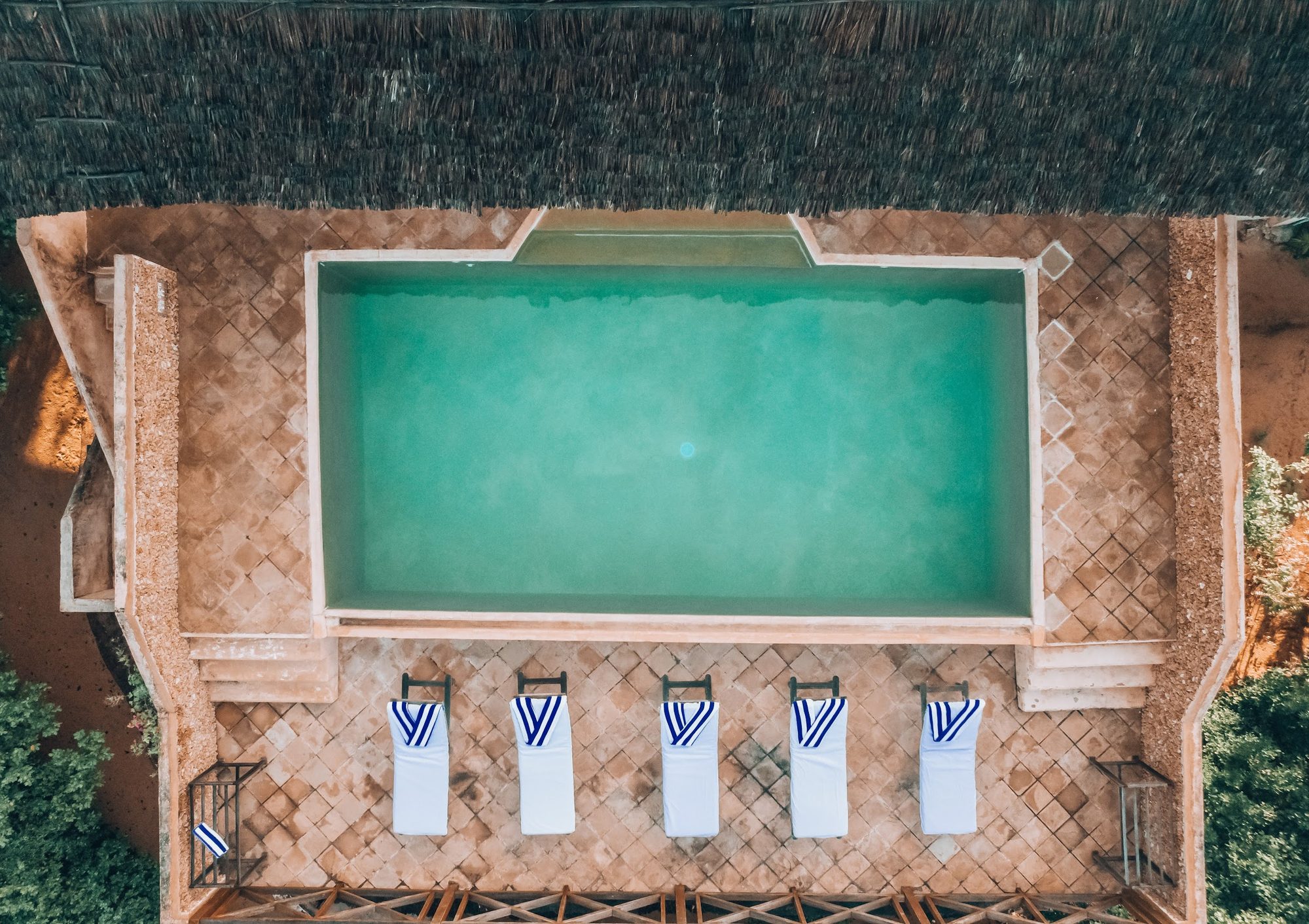 Aerial view of the lit central pool and arched colonnade at The Cabanas Lamu after dusk