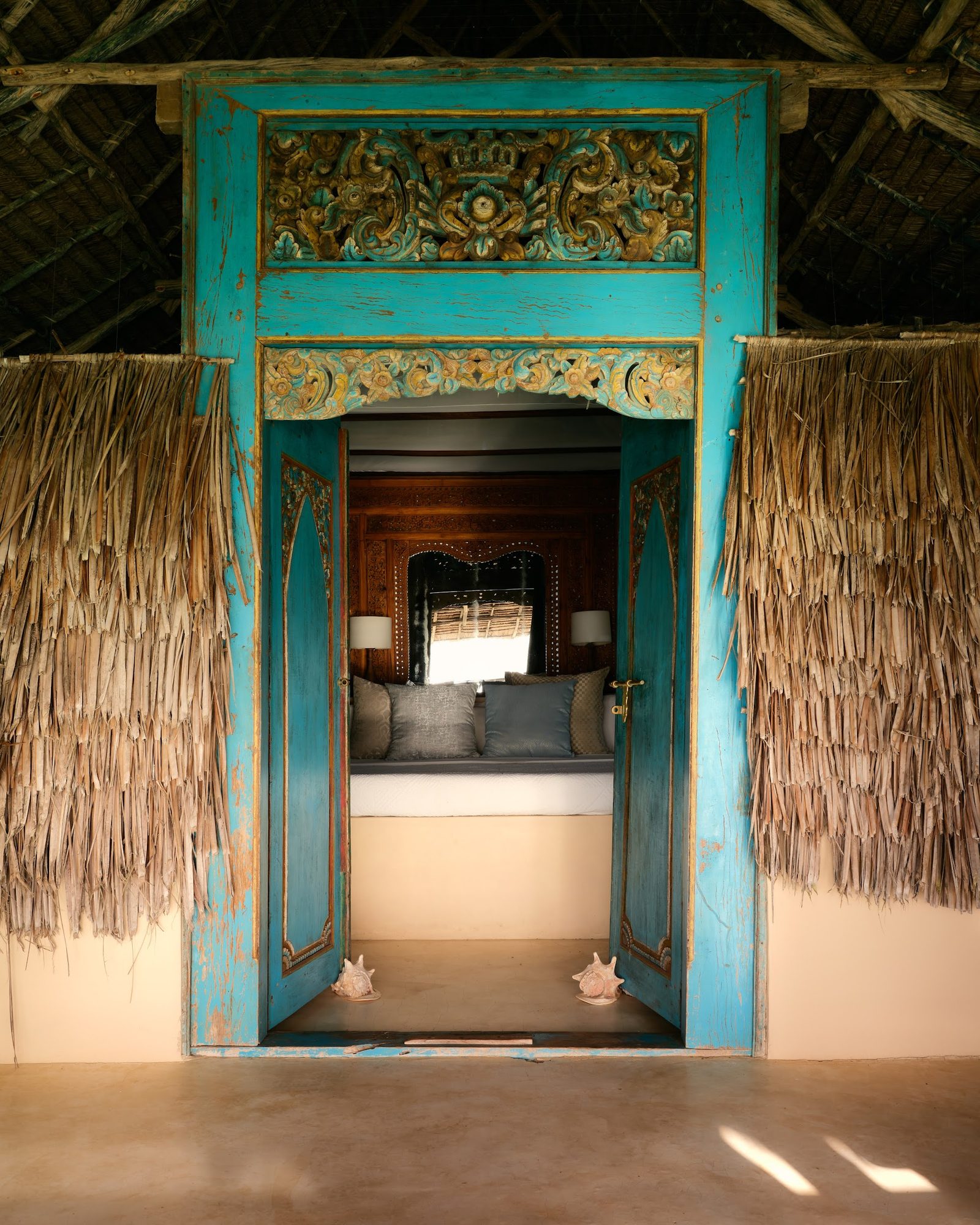 White macramé hammock strung between palms over the swimming pool, dhow on the ocean beyond