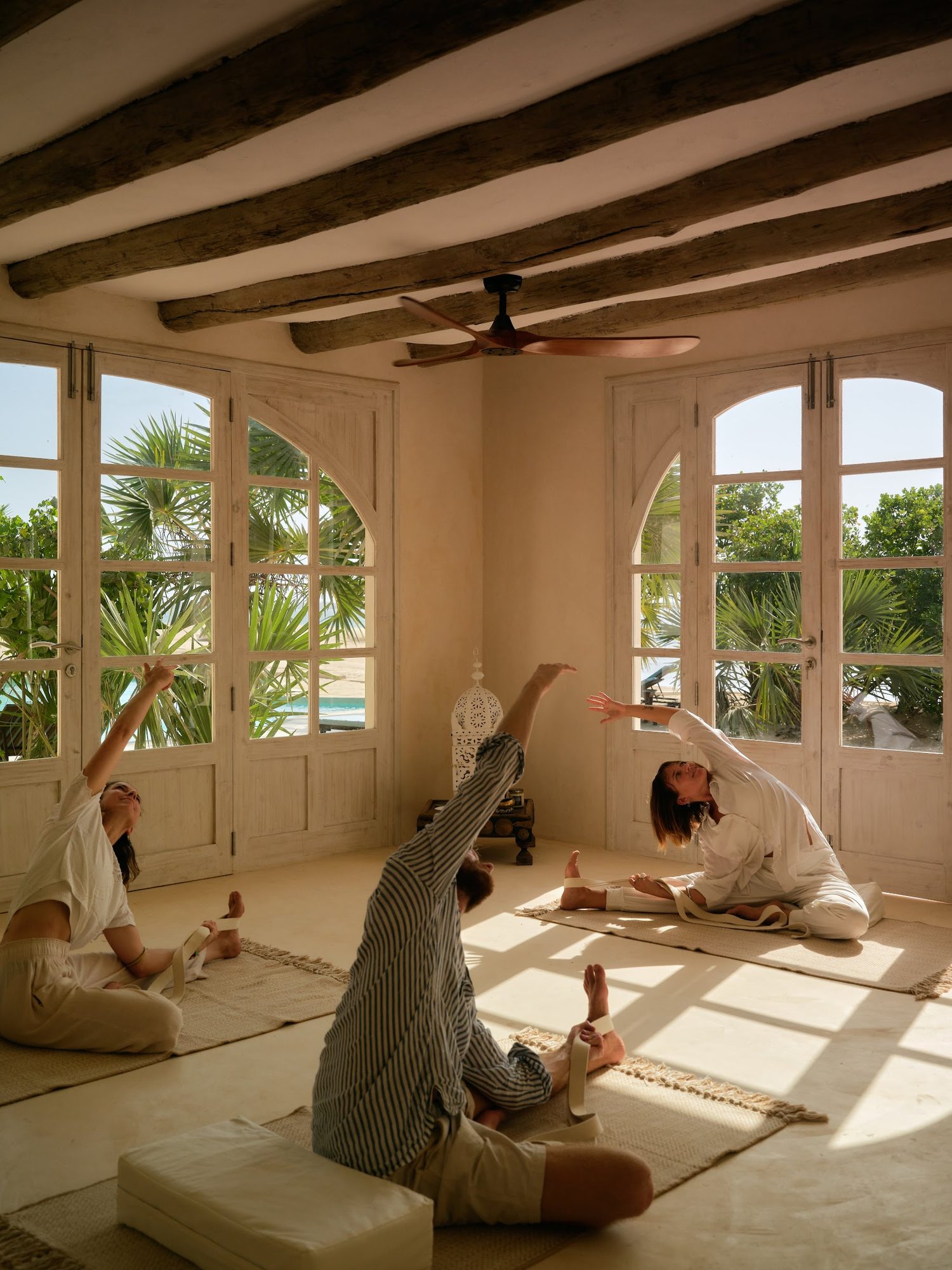 Yoga in white linen — cobra pose by an open Lamu door at the studio