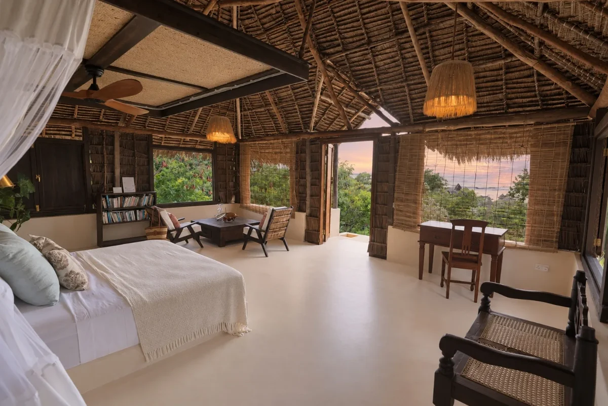 Aloha cabana, the netted bed and a reading corner beneath the thatch, sunset through the open door