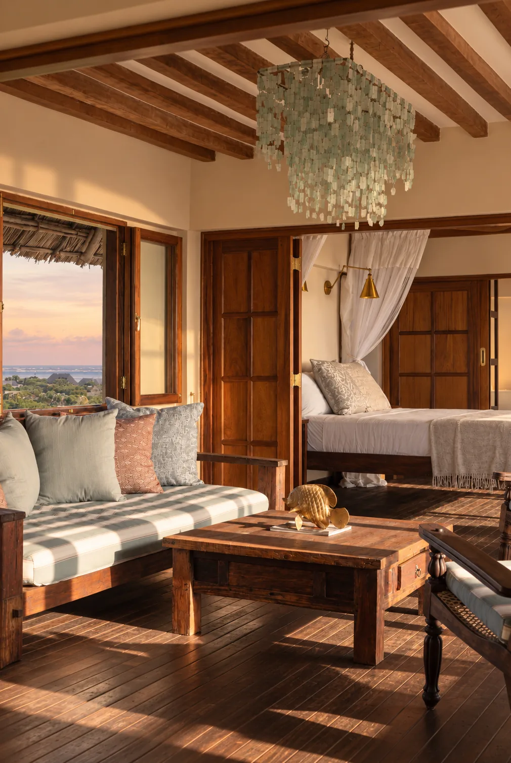 Kailani cabana, the sitting room beneath a sea-glass chandelier, folding doors open to the sunset