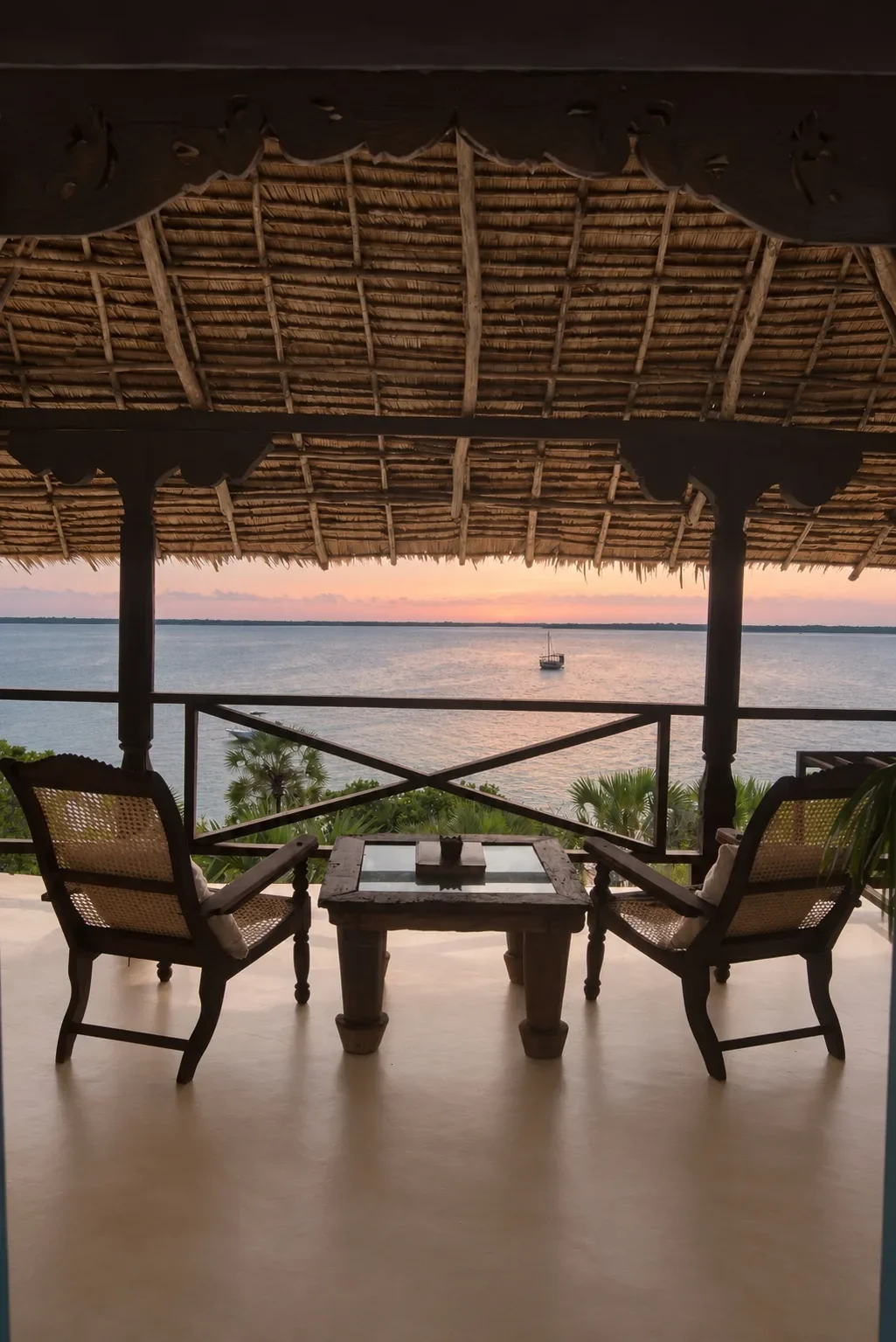 Two planter chairs on Lōkahi's upstairs verandah, a dhow moored in the channel