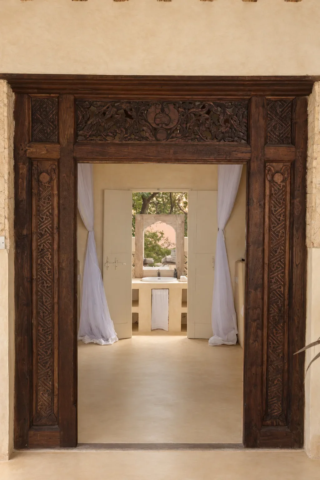 Makai cabana, a carved Lamu door frame looking through to the open-air bathroom