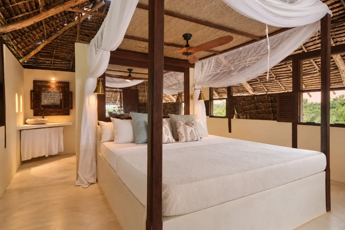 Makai first-floor bedroom, a four-poster under nets with brass lamps and shuttered windows