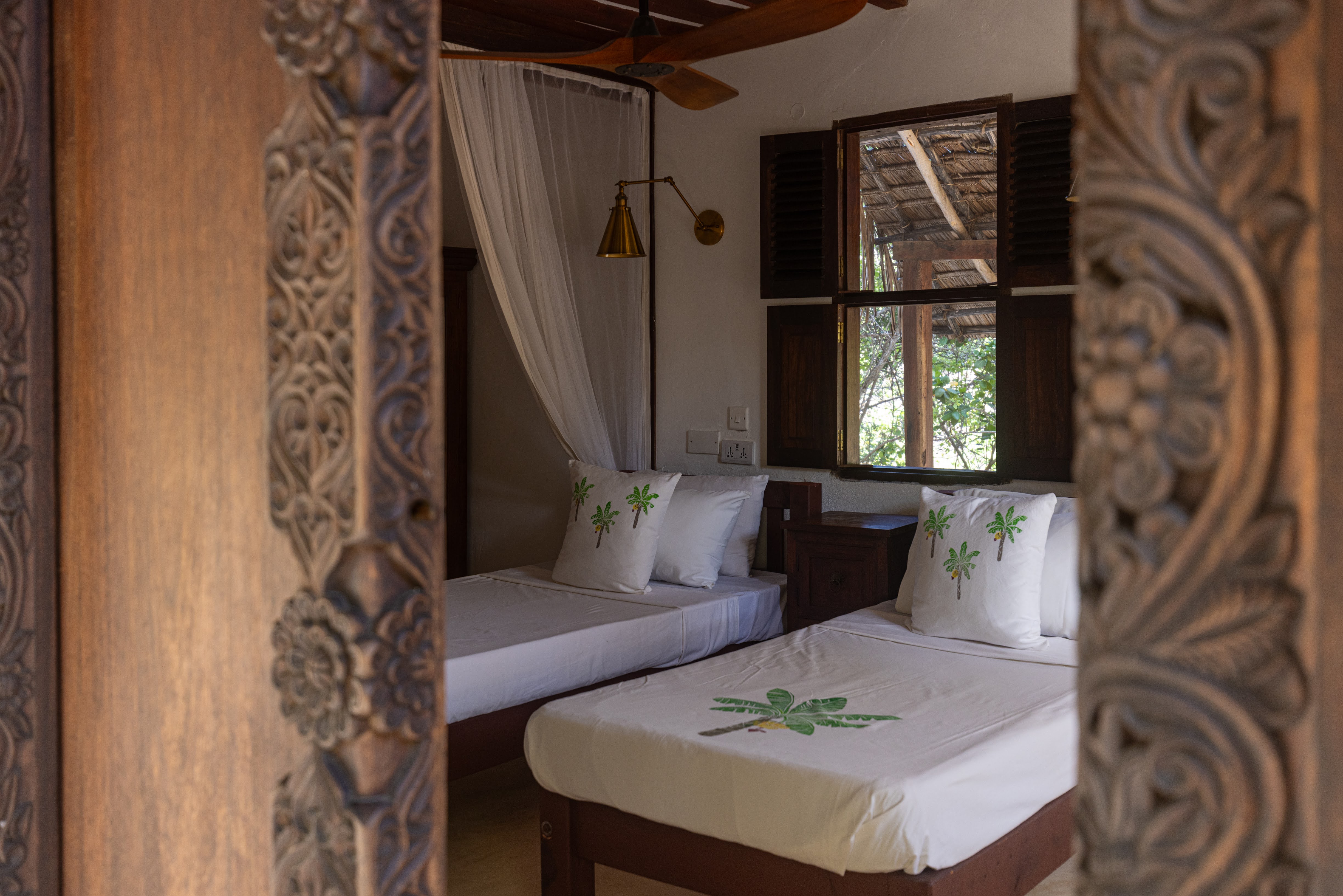 Mālama cabana — woven rope hanging daybed beside a sandy garden path