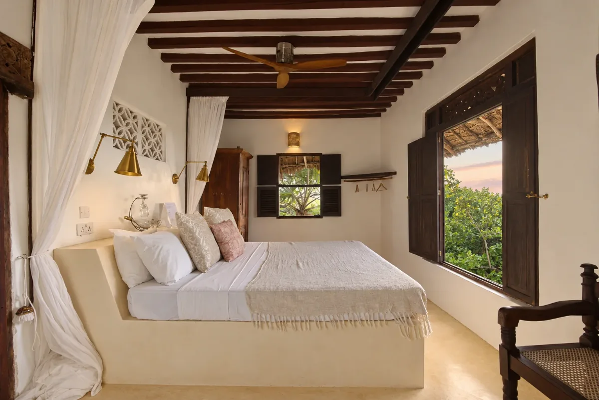 Mālama first-floor double, brass reading lamps, shutters open to the treetops