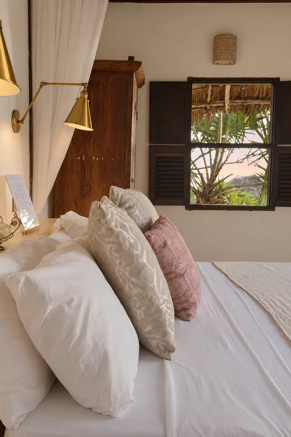Mālama first-floor bed, linen and blush cushions by the shuttered window