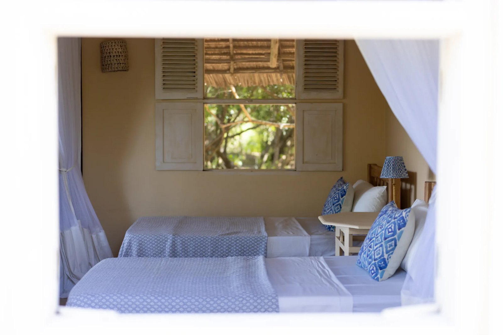 Moana cabana · ground-floor twin room, shutters open to the forest