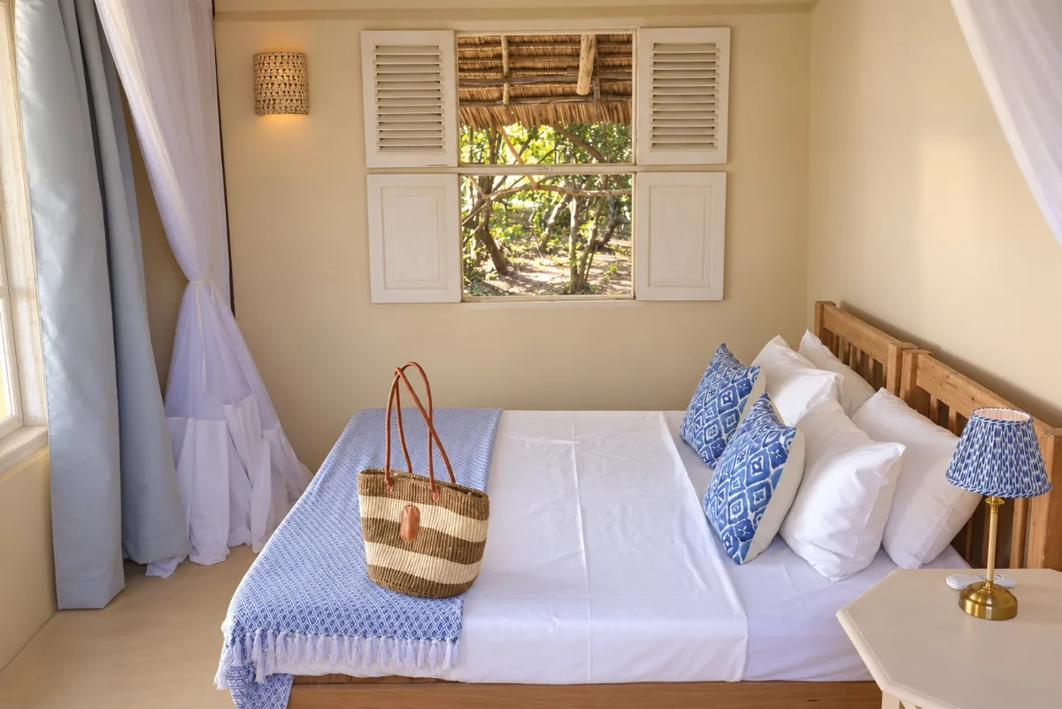 The ground-floor bedroom made up as a double, a shuttered window onto the trees