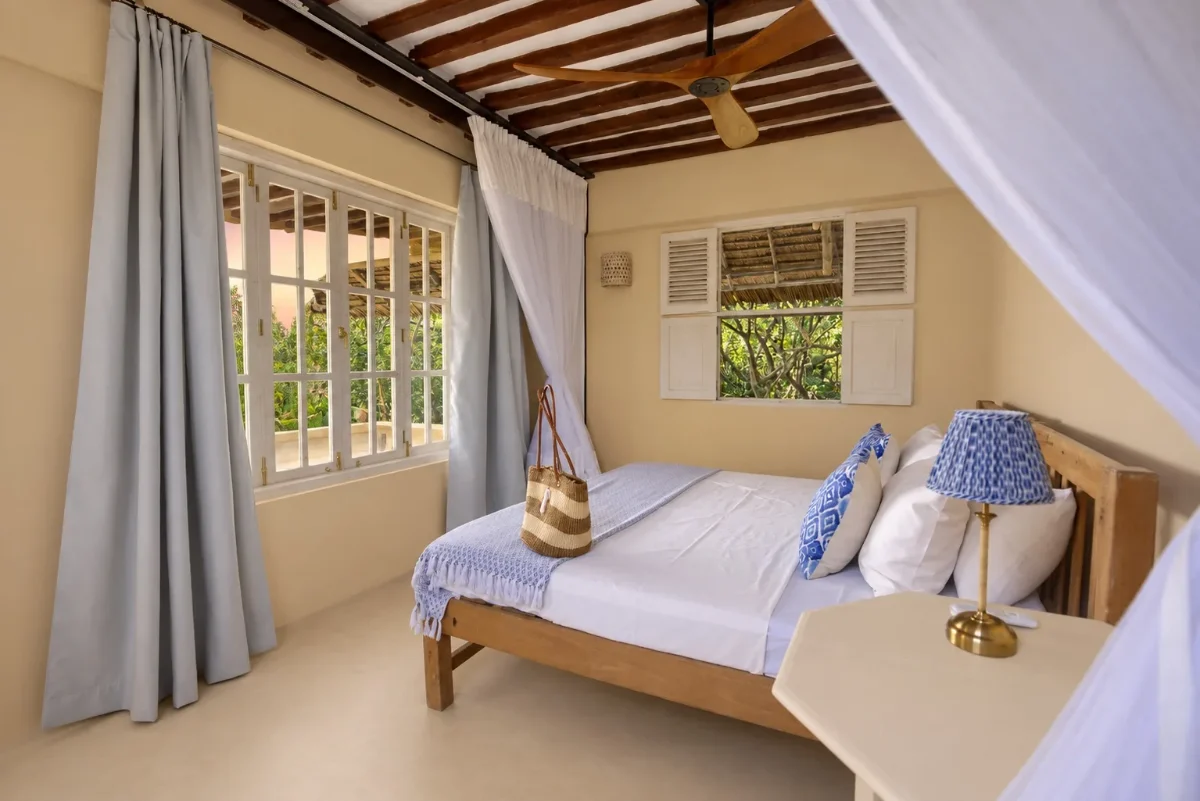 Ground-floor bedroom set up as a double, blue linen and shuttered windows to the garden
