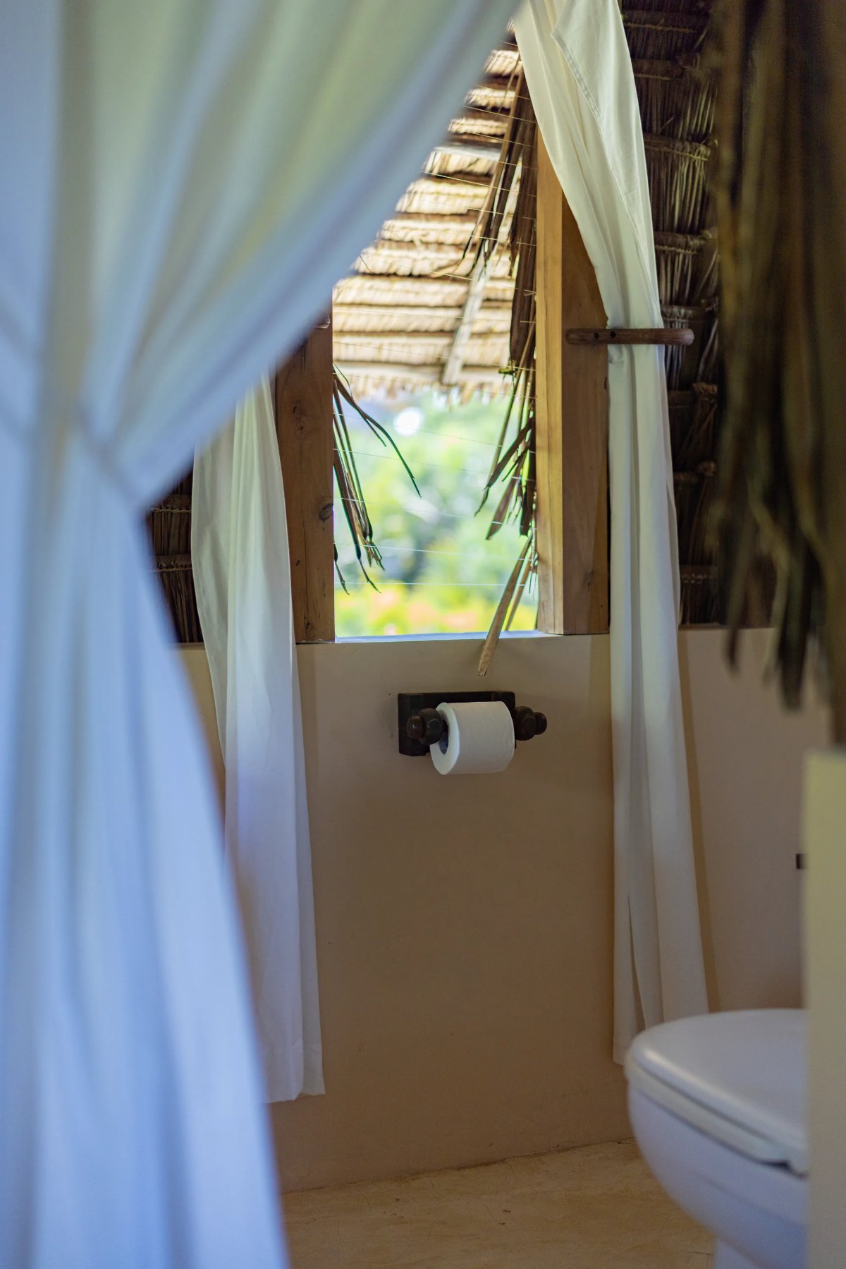 Moana cabana · upstairs ensuite, palms through the makuti window