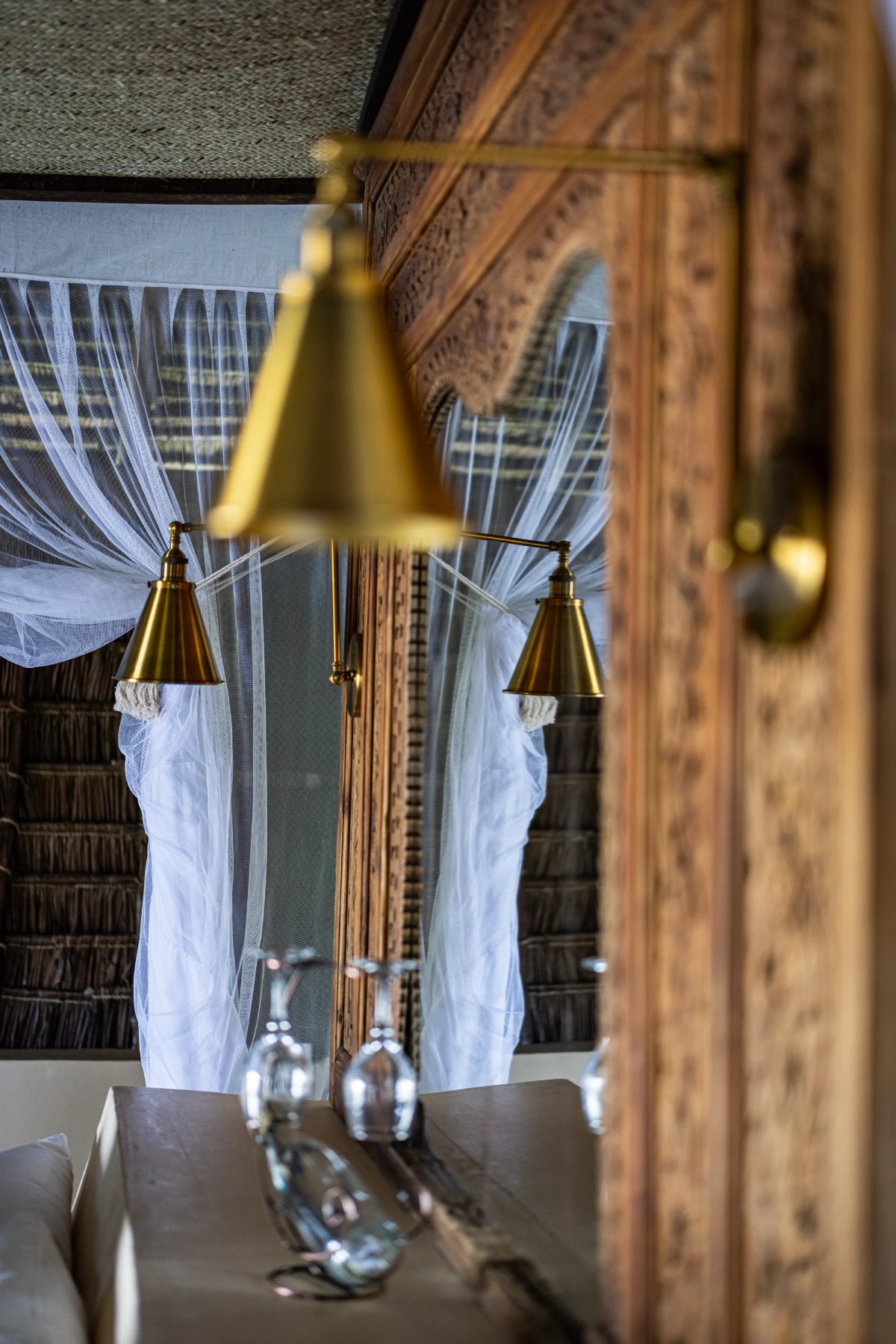 Moana cabana · brass lamp and mosquito net in the carved mirror
