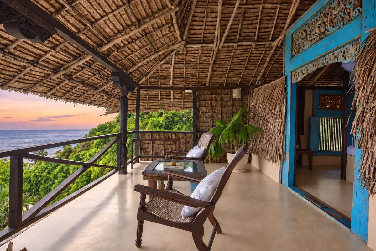 Upstairs verandah under the thatch, the carved blue door and the ocean beyond