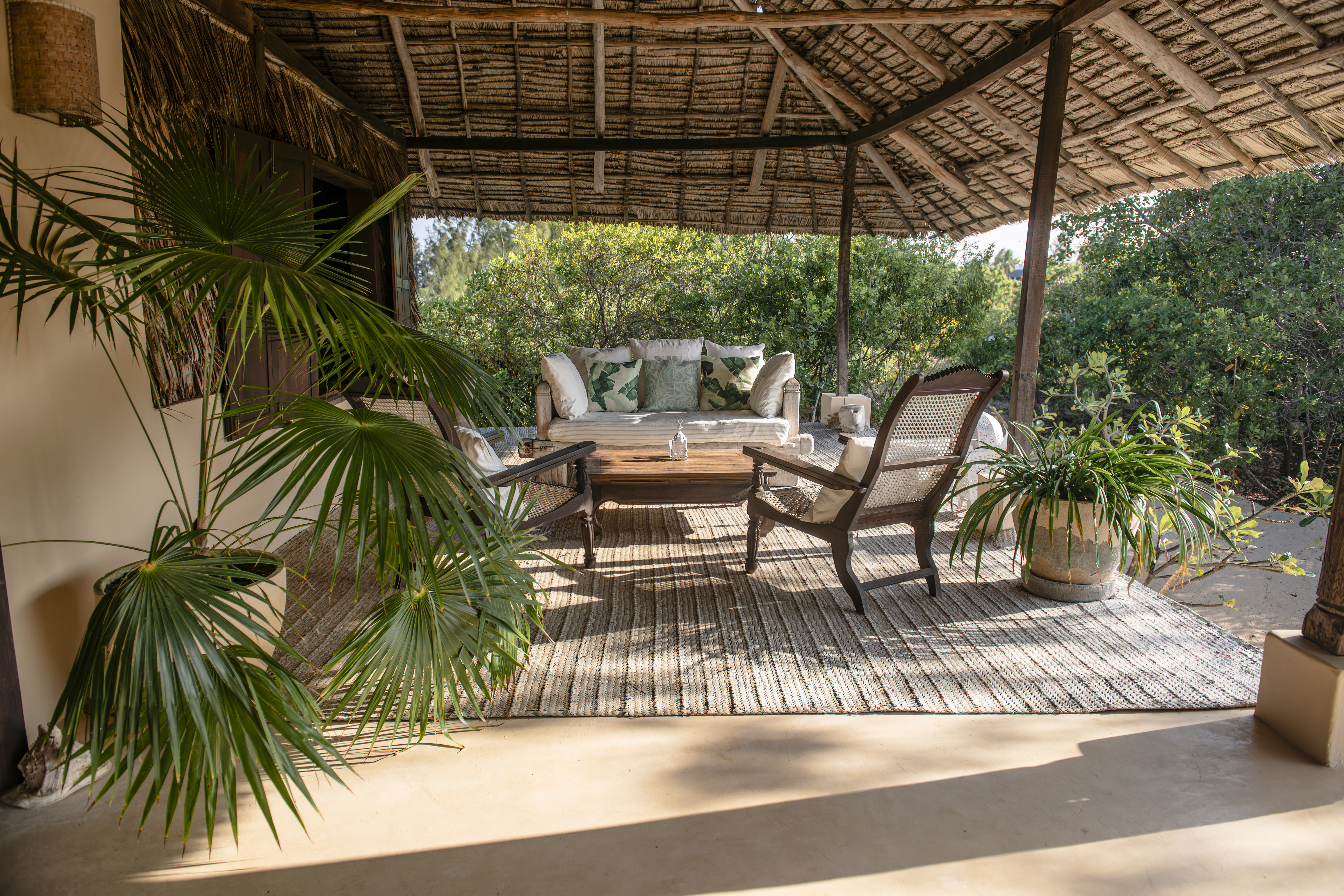 ʻOhana cabana — wide thatched veranda with cushions and a view to the ocean