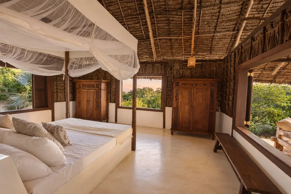 ʻOhana cabana, double bed, carved wardrobes and windows onto the trees