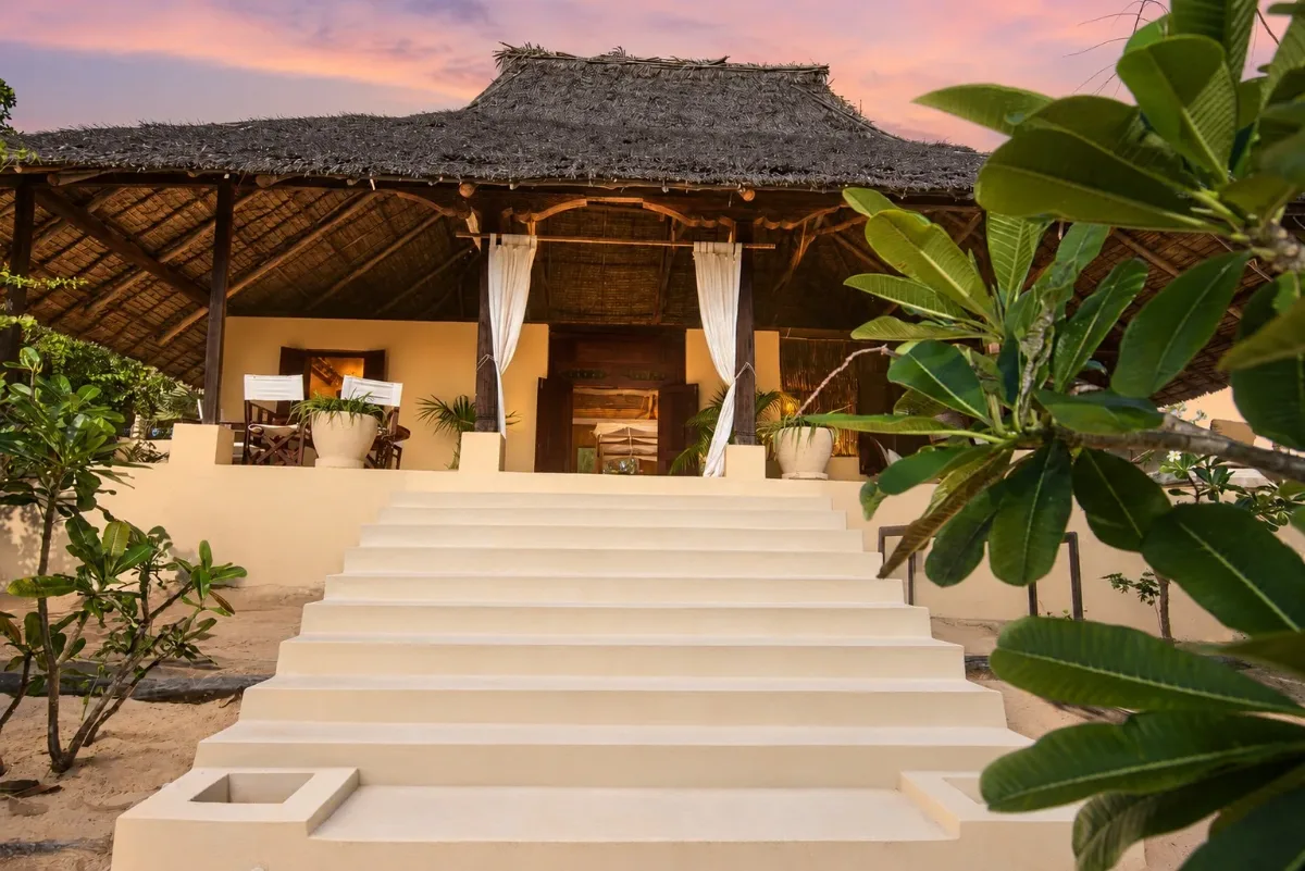ʻOhana cabana, lime-washed steps up to the thatched verandah at dusk