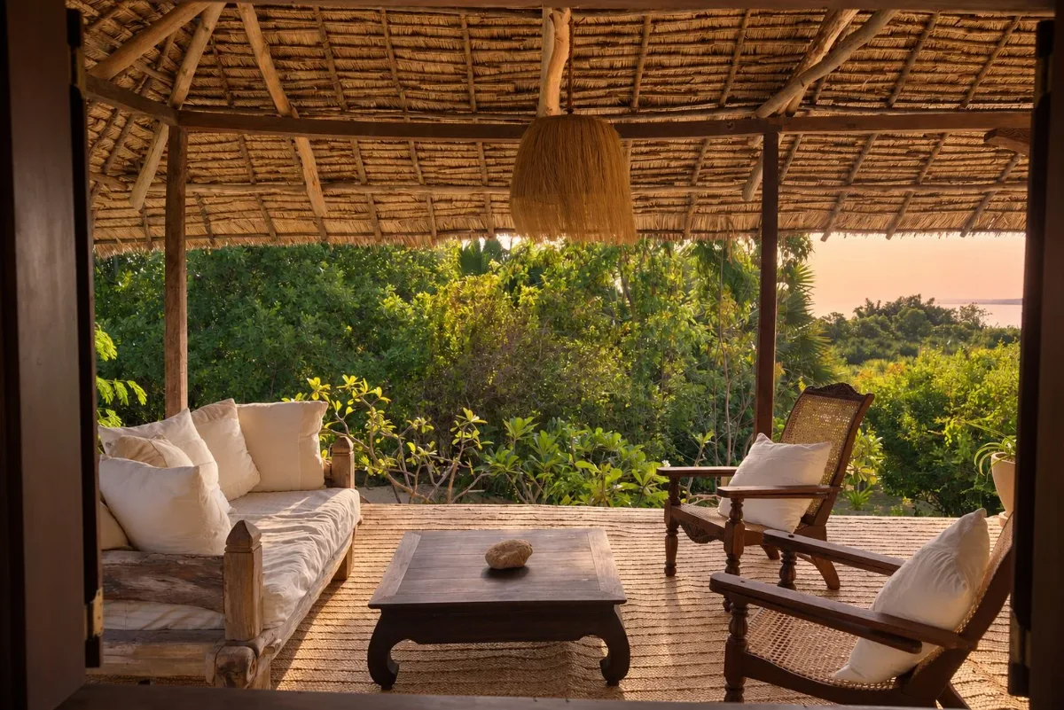 ʻOhana cabana, verandah daybed and cane chairs looking out to the sea at sunset