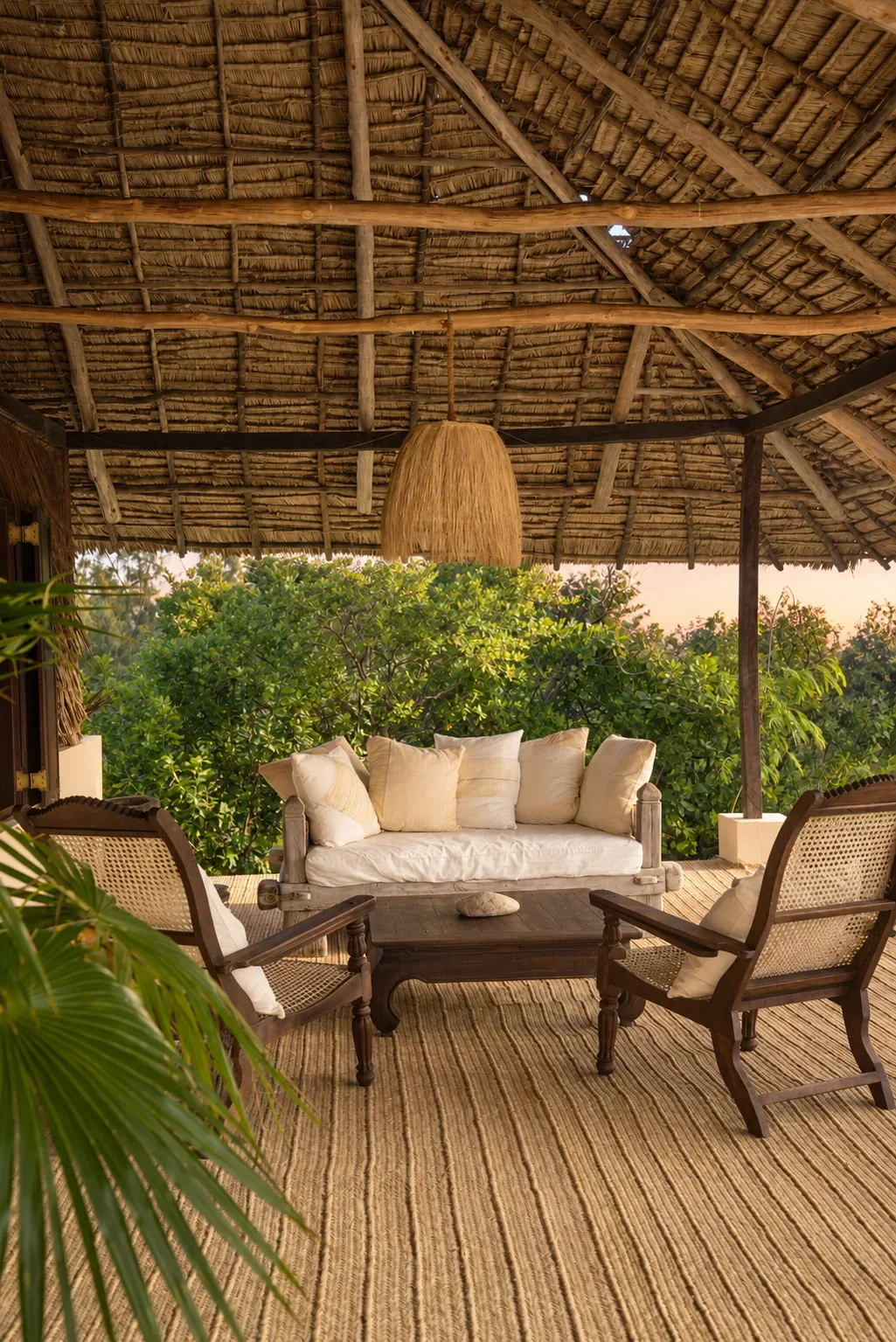 ʻOhana cabana, the verandah lounge under makuti thatch with planter chairs and a daybed